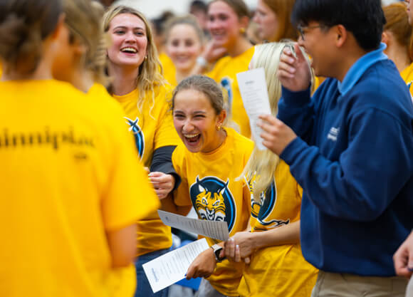 Individuals standing and laughing during Orientation